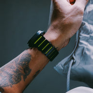 Bracelet Apple Watch Ultra souple en titane gris foncé avec inserts souples noirs et jaunes, design résistant et moderne.