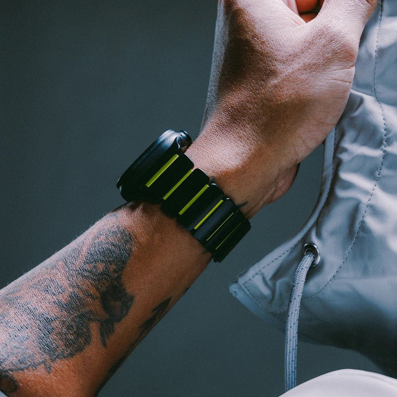 Bracelet Apple Watch Ultra souple en titane gris foncé avec inserts souples noirs et jaunes, design résistant et moderne.