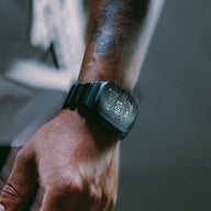 Bracelet Apple Watch en titane noir mat avec maillons robustes et design souple, porté au poignet.