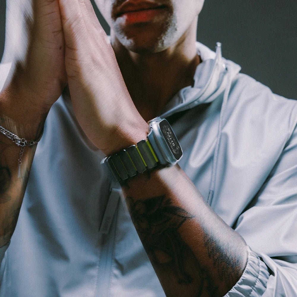 Bracelet Apple Watch souple en titane gris et caoutchouc noir, ajusté au poignet masculin, style moderne et robuste.
