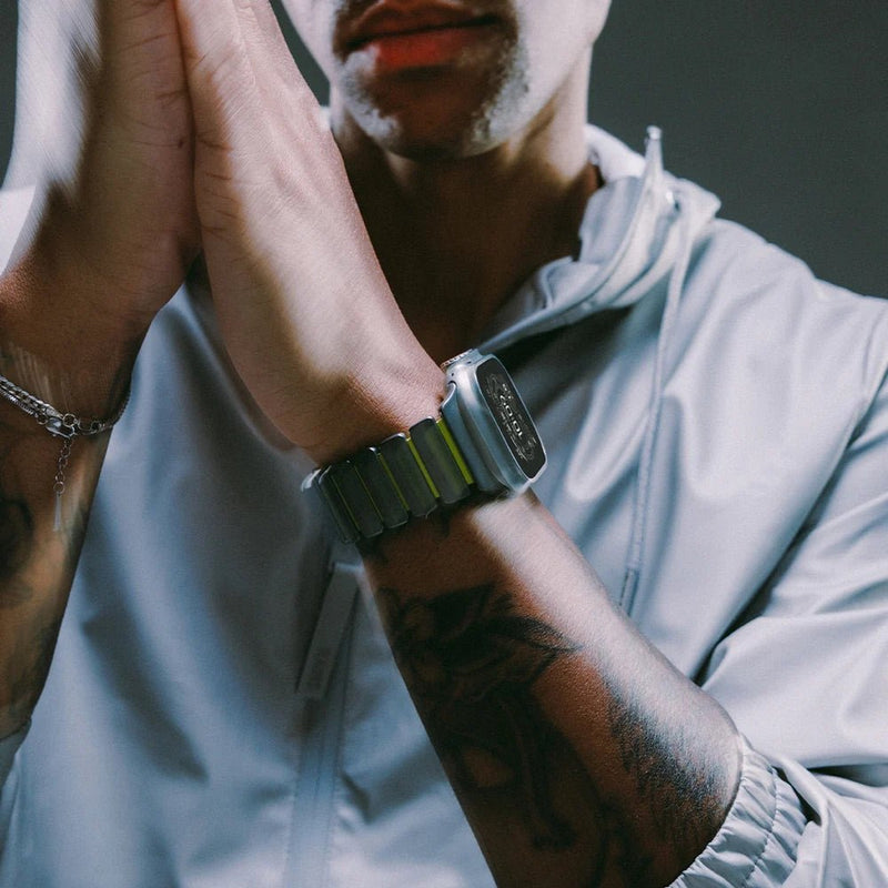 Bracelet Apple Watch souple en titane gris et caoutchouc noir, ajusté au poignet masculin, style moderne et robuste.