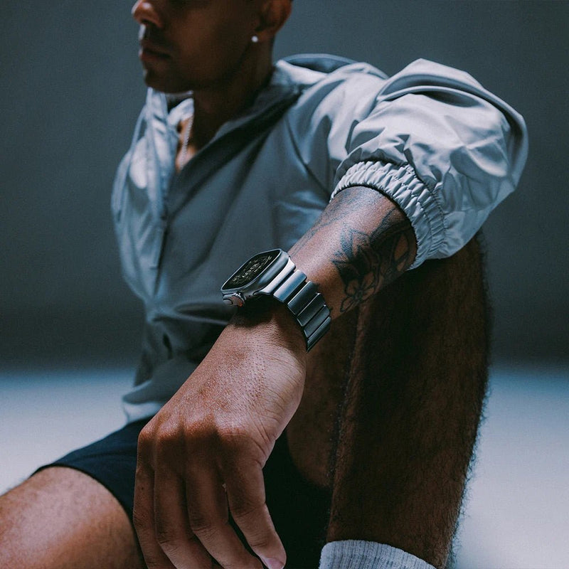 Bracelet Apple Watch en titane gris mat avec maillons larges, style robuste et moderne, porté sur poignet masculin.