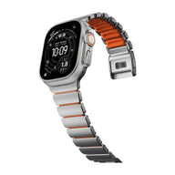 Bracelet Apple Watch Ultra titane gris clair avec intérieur orange souple en FKM, maillons larges et fermeture déployante.