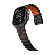 Bracelet Apple Watch Ultra en titane noir mat avec maillons souples et intérieur orange en FKM, design robuste et élégant.