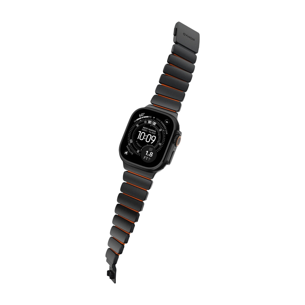 Bracelet Apple Watch en titane gris foncé avec inserts orange, design souple et segmenté.