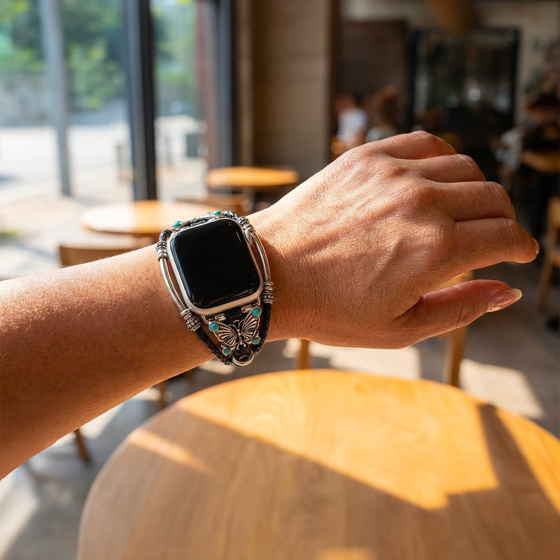 Bracelet Apple Watch en simili cuir vegan noir tressé avec papillon argenté et perles turquoise élégantes.
