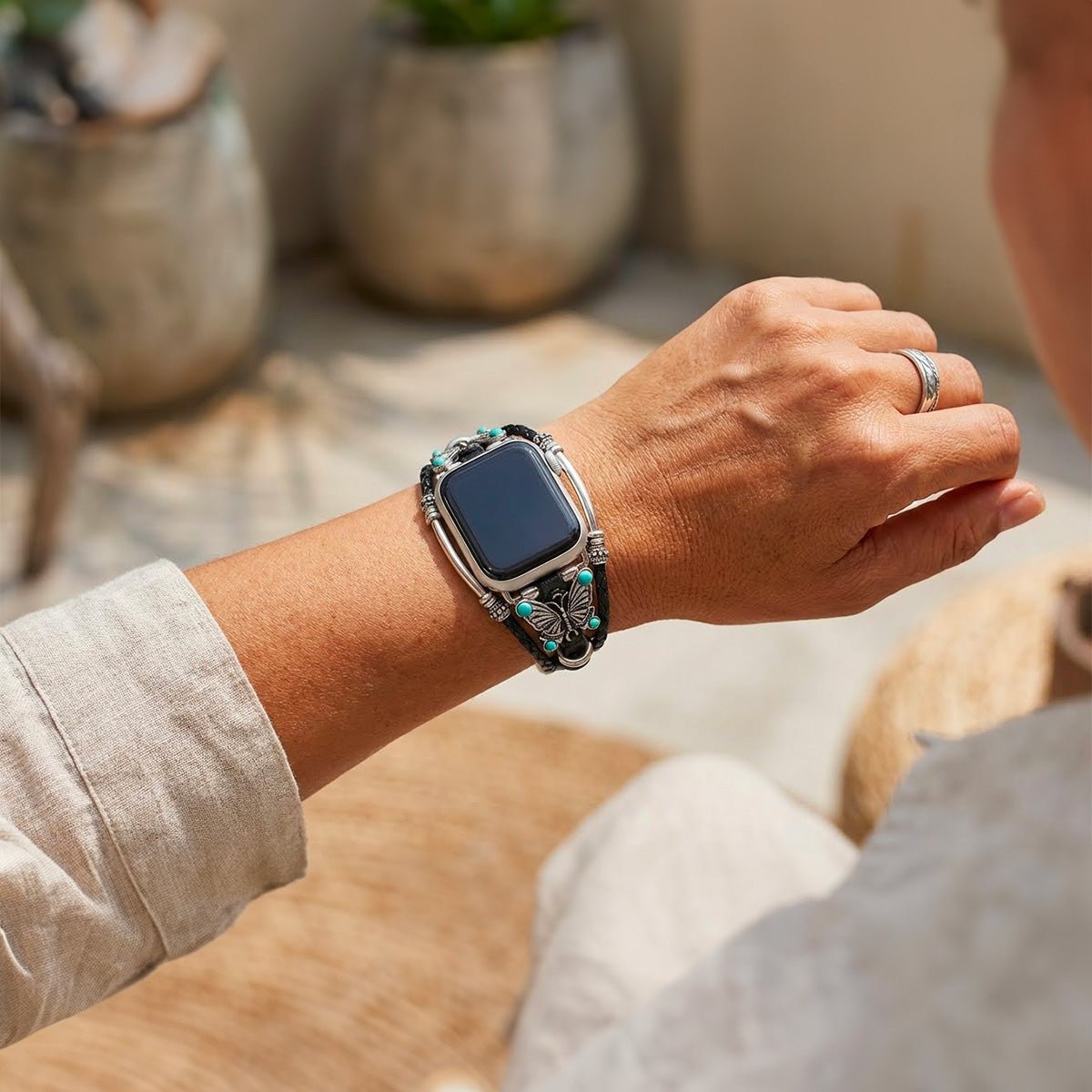 Bracelet Apple Watch noir simili cuir tressé avec papillon argenté et perles turquoise élégantes.