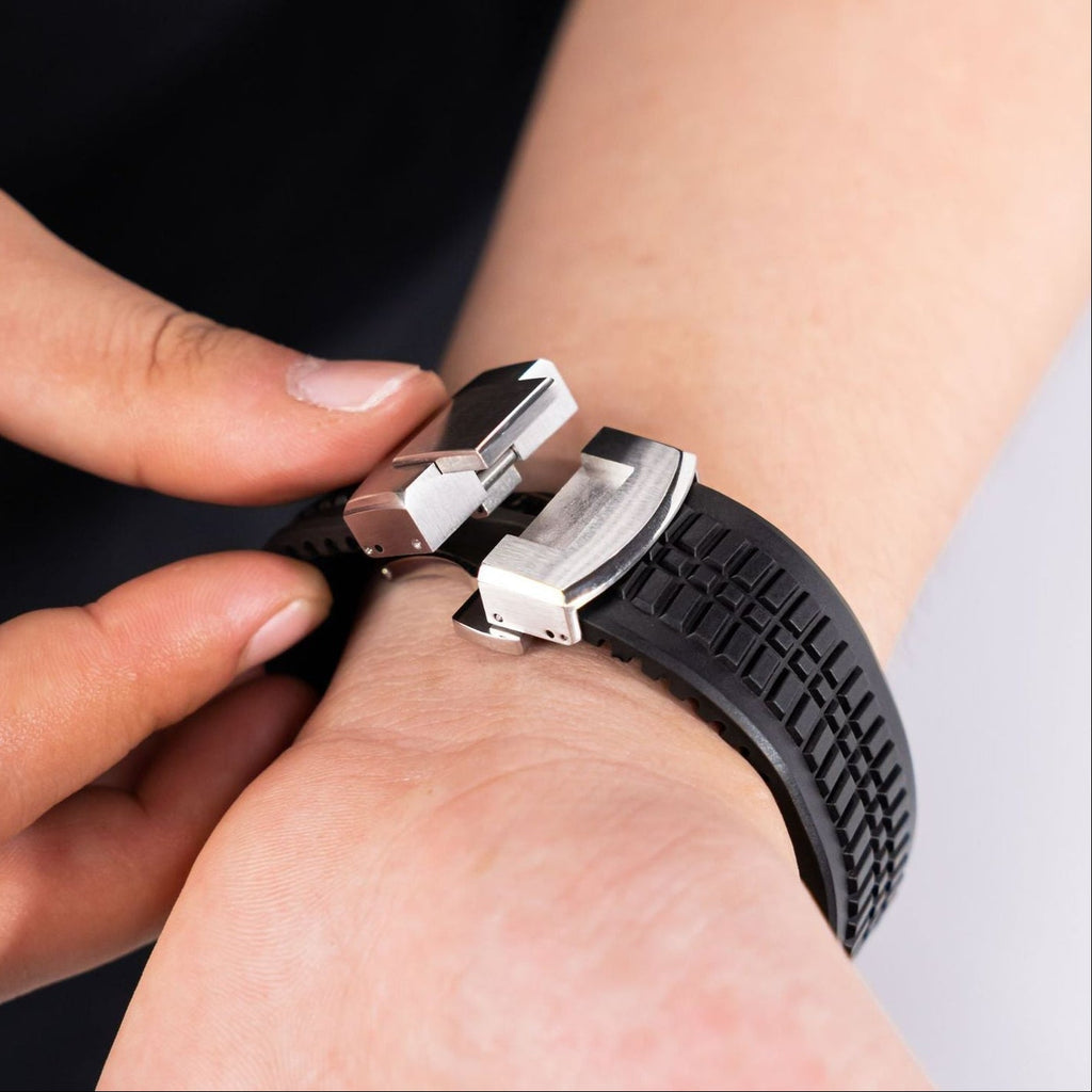 Bracelet Apple Watch sport noir en silicone texturé, boucle ajustable double en métal argenté.