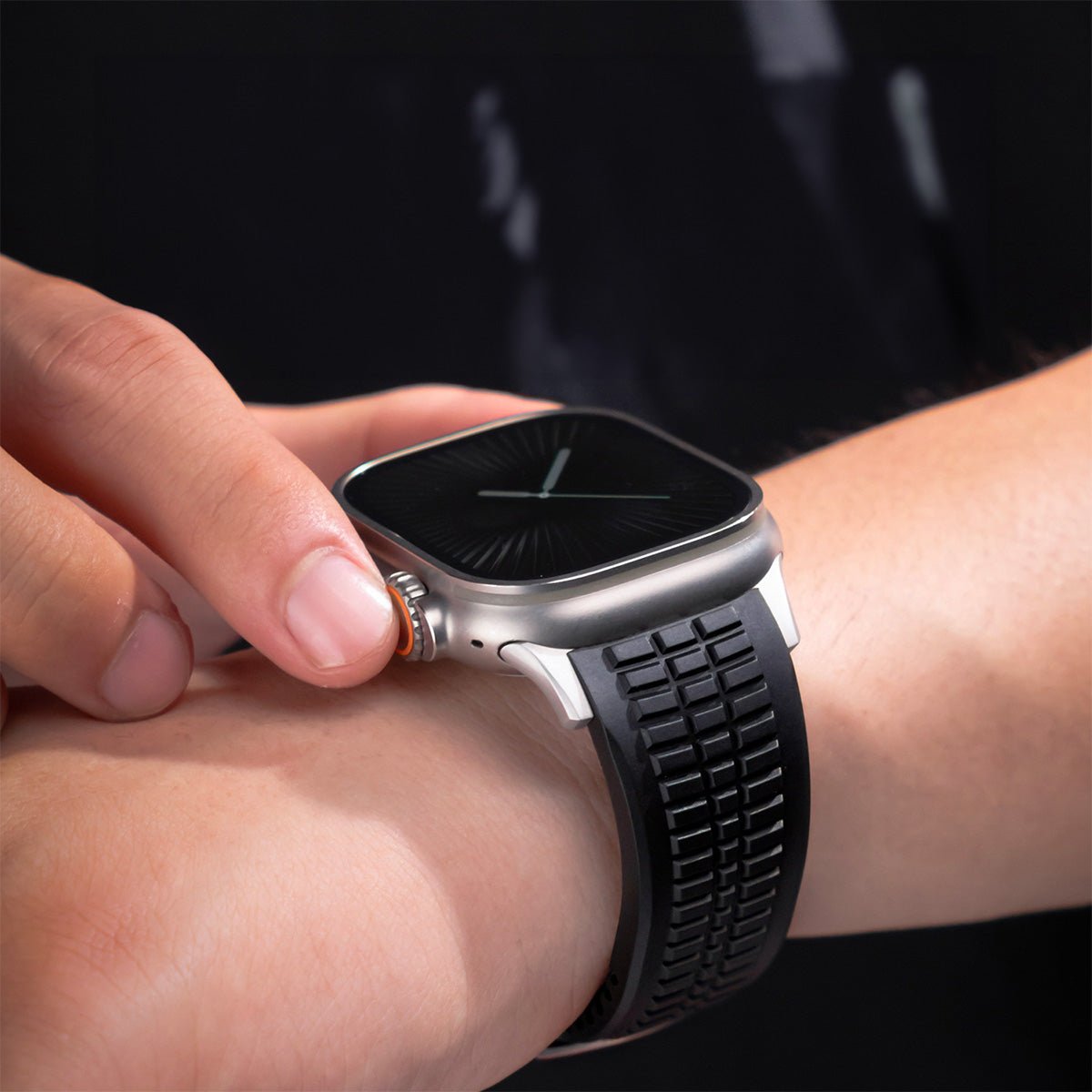 Bracelet Apple Watch sport noir en silicone avec motif texturé en damier, boucle double ajustable en métal argenté.