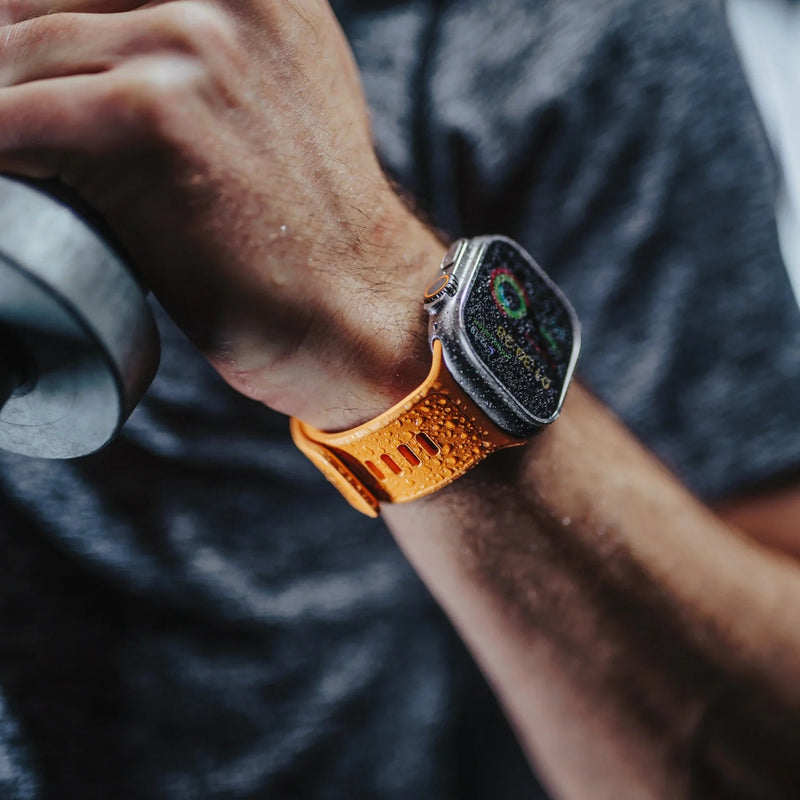 Bracelet Apple Watch en cuir orange et fluoroélastomère avec boucle ajustable, design sport hybride.