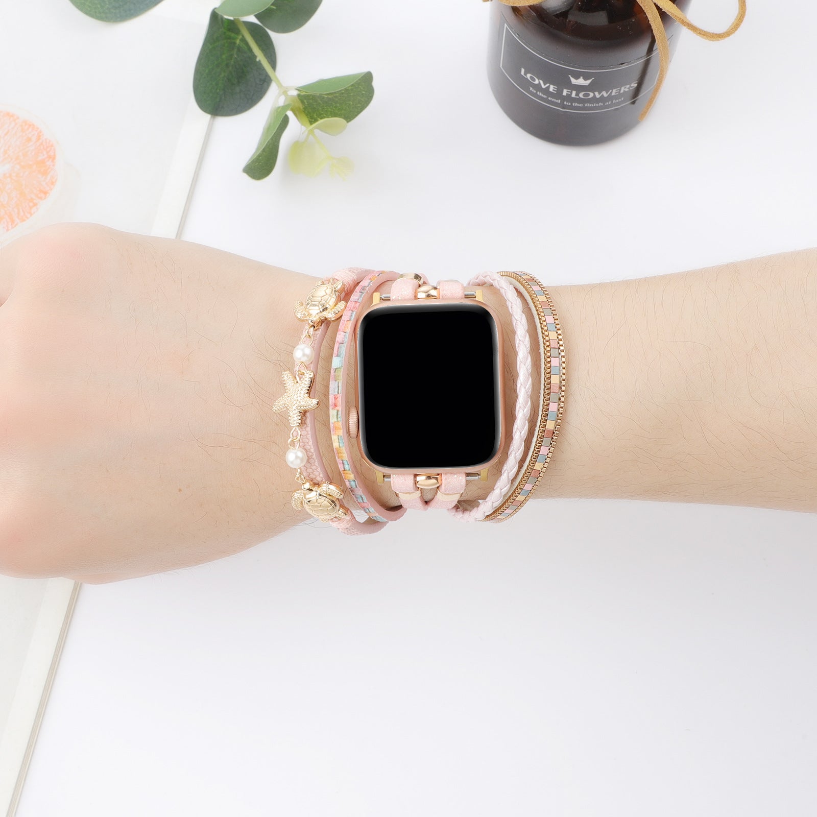 Bracelet Apple Watch style tropical chic en simili vegan rose avec tortue dorée, étoile de mer et perles décoratives.