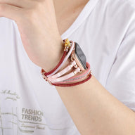 Bracelet Apple Watch doré avec perles et strass rouges, breloque ours en métal brillant, style raffiné et féminin.