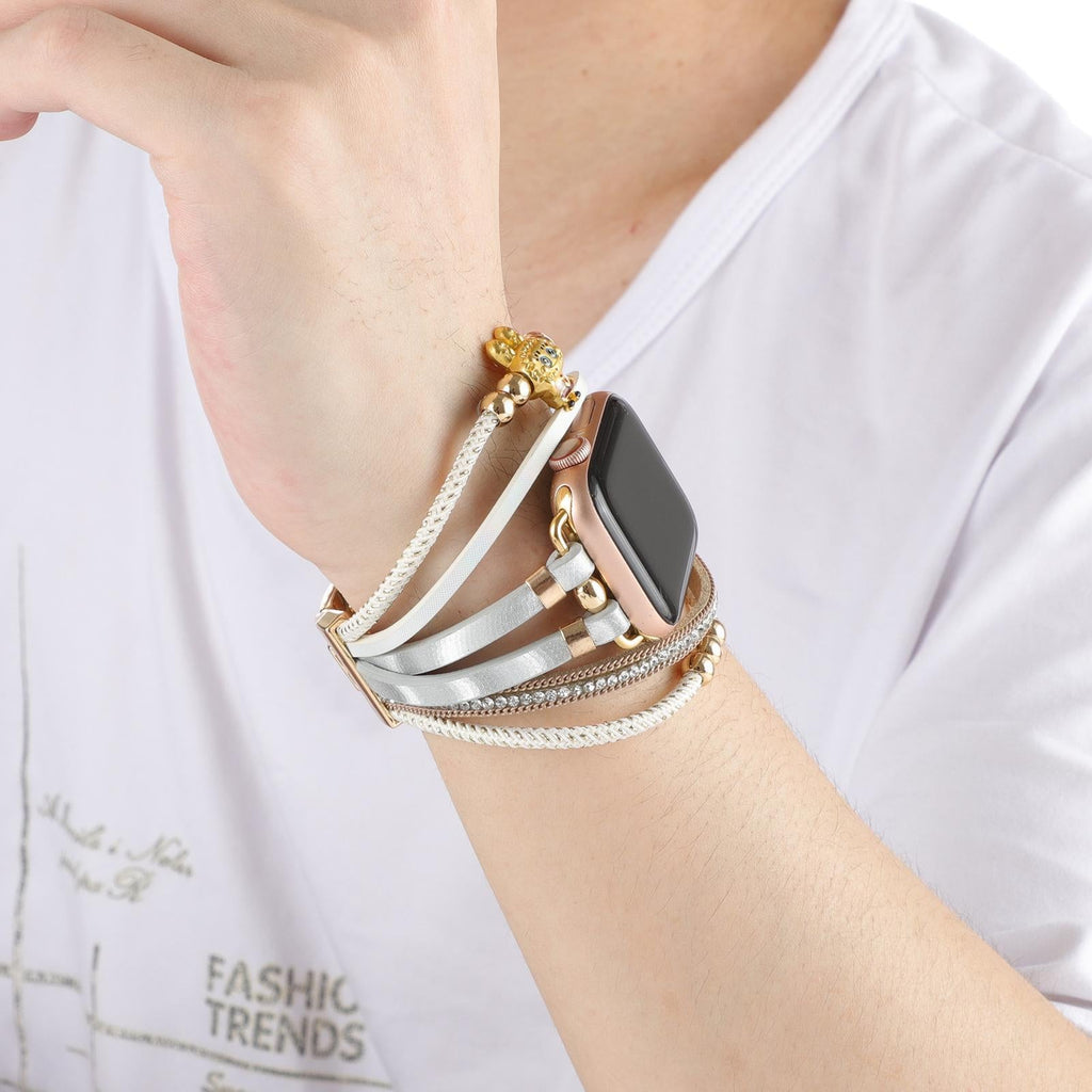 Bracelet Apple Watch doré avec perles, strass brillants et breloque ourson élégant, porté au poignet.