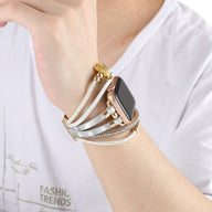 Bracelet Apple Watch doré avec perles, strass brillants et breloque ourson élégant, porté au poignet.