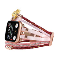 Bracelet doré pour Apple Watch avec perles dorées, strass brillants et breloque ours teddy sur cordon tressé rouge.