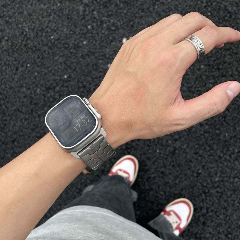 Bracelet Apple Ultra en titane massif gris, maillons larges, fermeture boucle sécurisée style techwear.