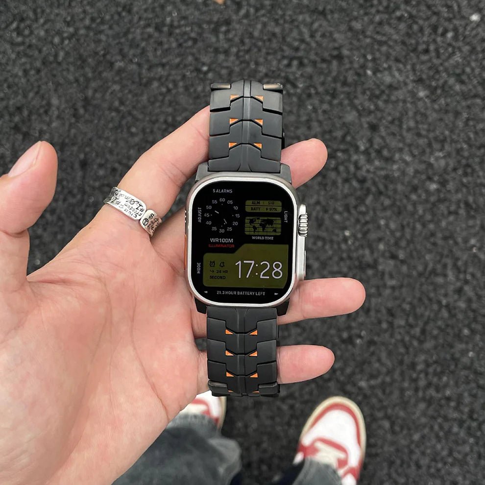 Bracelet connecté Apple Ultra en titane massif noir mat avec maillons ajourés et détails orange, fermeture boucle sécurisée,