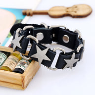 Bracelet ardillon en cuir noir avec motif étoiles métalliques et anneaux ronds argentés.