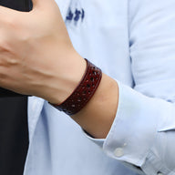 Bracelet ardillon en cuir café à perforations fines, style rétro, porté au poignet homme.