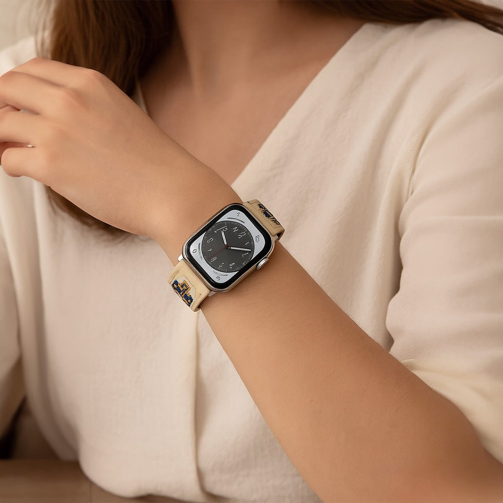 Bracelet Apple Watch beige en cuir brodé, style ajustable, modèle Tilma, porté au poignet féminin.