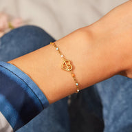 Bracelet fin en argent doré avec pendentif cœur et motif battement de cœur, porté au poignet féminin.