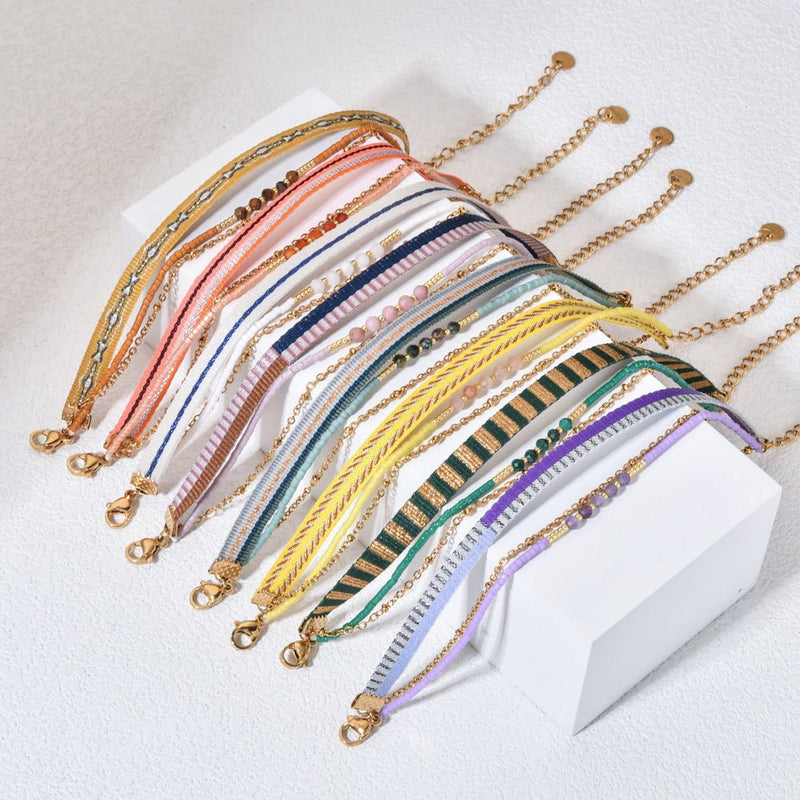 Bracelet bohème multirangs avec perles colorées, rubans rayés variés et chaîne dorée délicate, fermoir mousqueton.