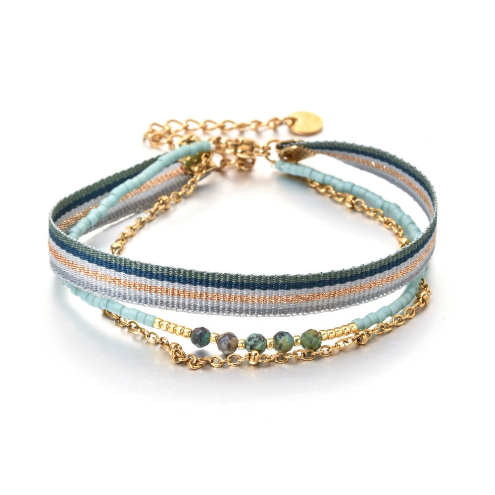 Bracelet multirangs bohème avec rubans rayés bleu et beige, perles vertes, chaîne dorée fine et fermoir mousqueton.