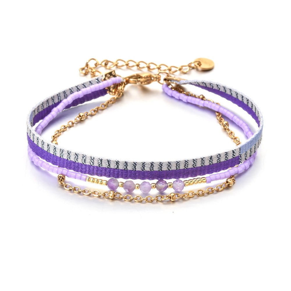 Bracelet bohème multirangs avec perles violettes, ruban rayé gris et violet, chaîne dorée fine, fermoir mousqueton.