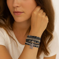 Bracelet multi-couches boho chic en simili cuir tressé noir avec tissu ethnique, strass et pompon gris, fermoir aimanté.