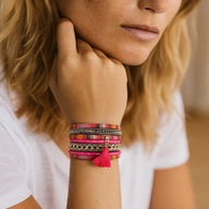 Bracelet boho rose multi-couches en simili cuir tressé, tissu ethnique, strass noirs et pompon aimanté.