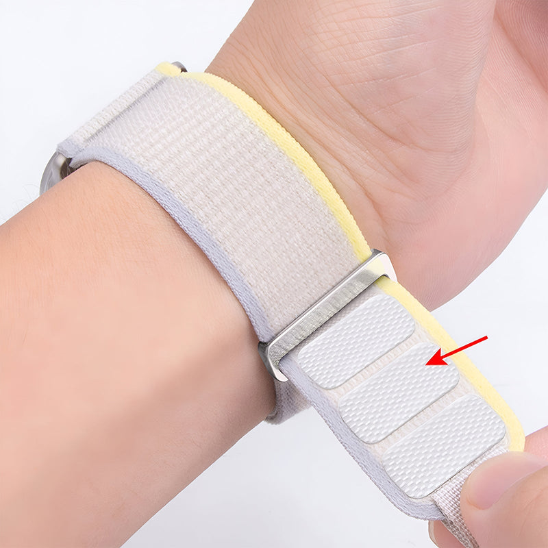 Bracelet Apple Watch Trail Edition en nylon gris clair avec doublure jaune et fermeture velcro ajustable.