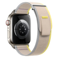 Bracelet Apple Watch Trail Edition en nylon beige avec bordure jaune et fermeture velcro grise.
