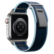 Bracelet Apple Watch en nylon bleu marine avec bordure bleu clair et fermeture velcro grise.