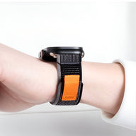 Bracelet Apple Watch en nylon noir avec patch orange et fermeture velcro sur poignet.