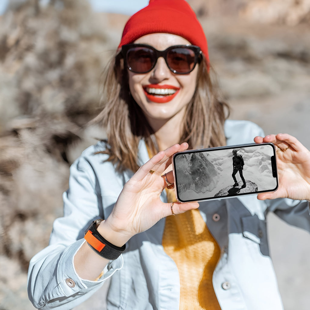 Bracelet Trail Edition en nylon orange avec fermeture velcro pour Apple Watch, porté au poignet femme.