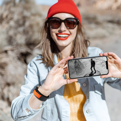 Bracelet Trail Edition en nylon orange avec fermeture velcro pour Apple Watch, porté au poignet femme.