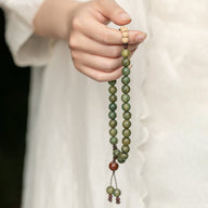 Bracelet bouddha en perles de bois de santal vert avec perles crème et cordon ajustable.