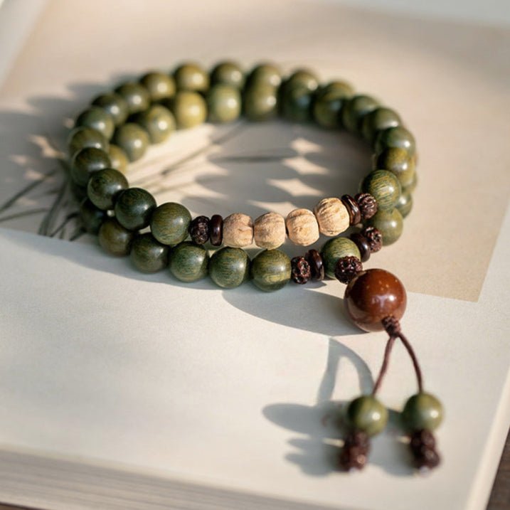 Bracelet double tour en bois de santal vert avec perles claires et pendeloque marron en bois lisse.