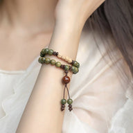 Bracelet double tour en bois de santal vert avec perles et pendentif Bouddha sculpté beige.