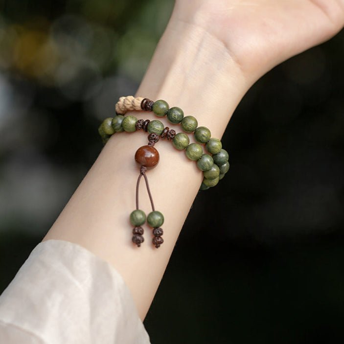 Bracelet bouddha en perles vertes en bois de santal avec pendentif marron et cordon ajustable.