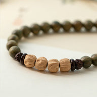 Bracelet femme en perles vertes avec accents bois de santal clair et sombre, design Bouddha Prana.