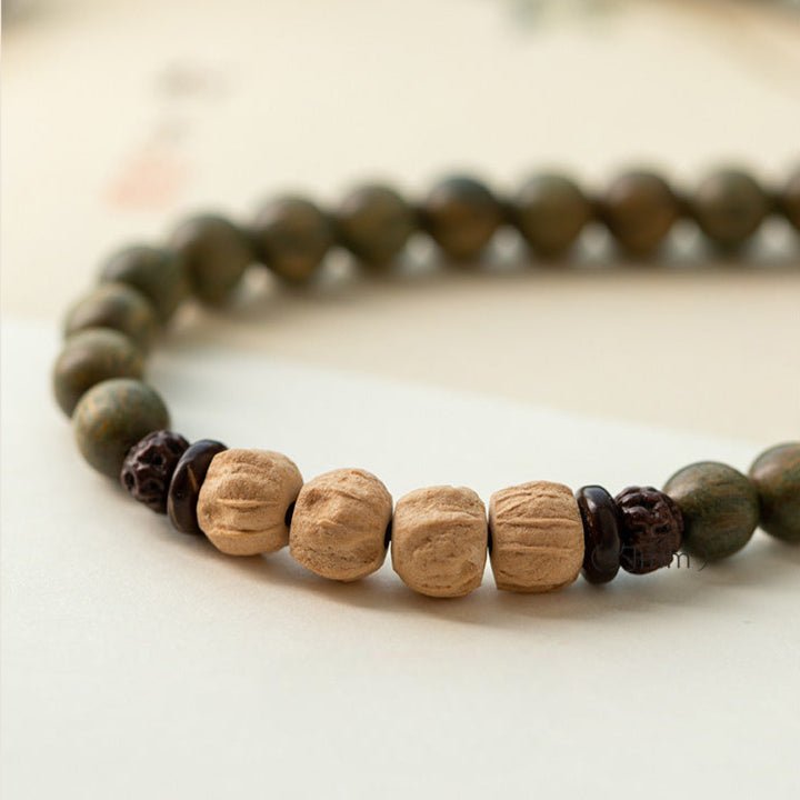 Bracelet femme en perles vertes avec accents bois de santal clair et sombre, design Bouddha Prana.