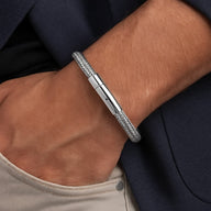 Bracelet câble en acier inoxydable argenté avec fermoir lisse porté au poignet.