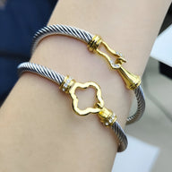 Bracelet câble argenté en acier inoxydable avec détails dorés et ornements scintillants, style Nymera.