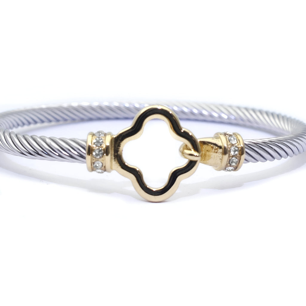 Bracelet câble argenté en acier inoxydable avec détail trèfle doré orné de petits cristaux blancs.