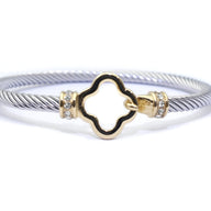 Bracelet câble argenté en acier inoxydable avec détail trèfle doré orné de petits cristaux blancs.