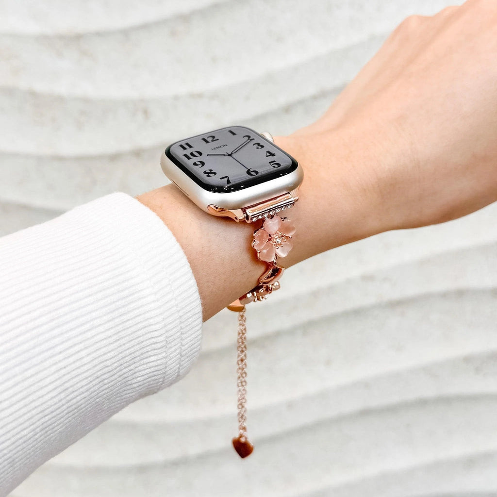 Bracelet chaîne métallique rose avec fleurs de cerisier délicates pour Apple Watch, style féminin et élégant.