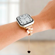 Bracelet chaîne métal doré à fleurs de cerisier délicates pour Apple Watch, avec pendentif cœur noir suspendu.