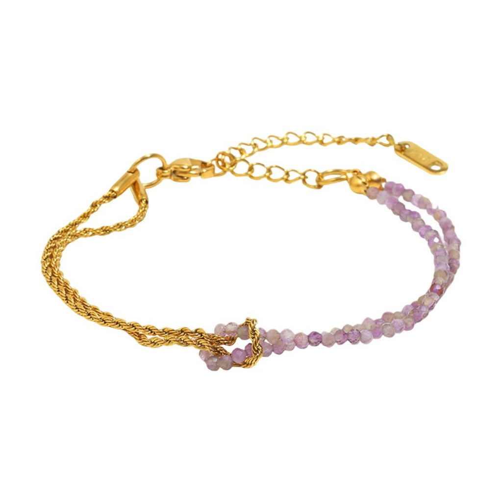 Bracelet doré torsadé combiné à une rangée de perles naturelles violettes, fermoir ajustable avec chaîne fine.