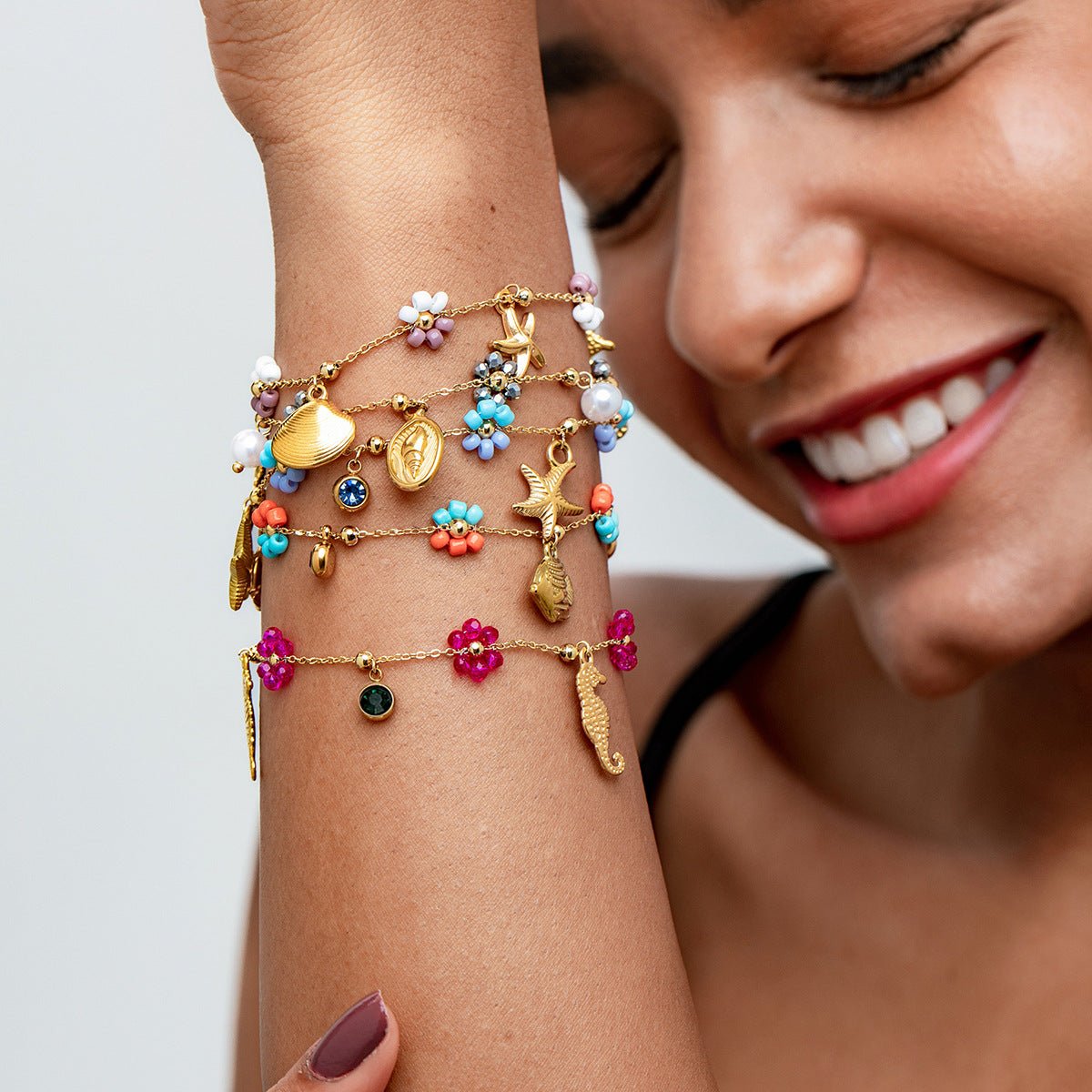 Bracelets fins dorés en acier inoxydable avec charms colorés soleil, fleurs et motifs estivaux.